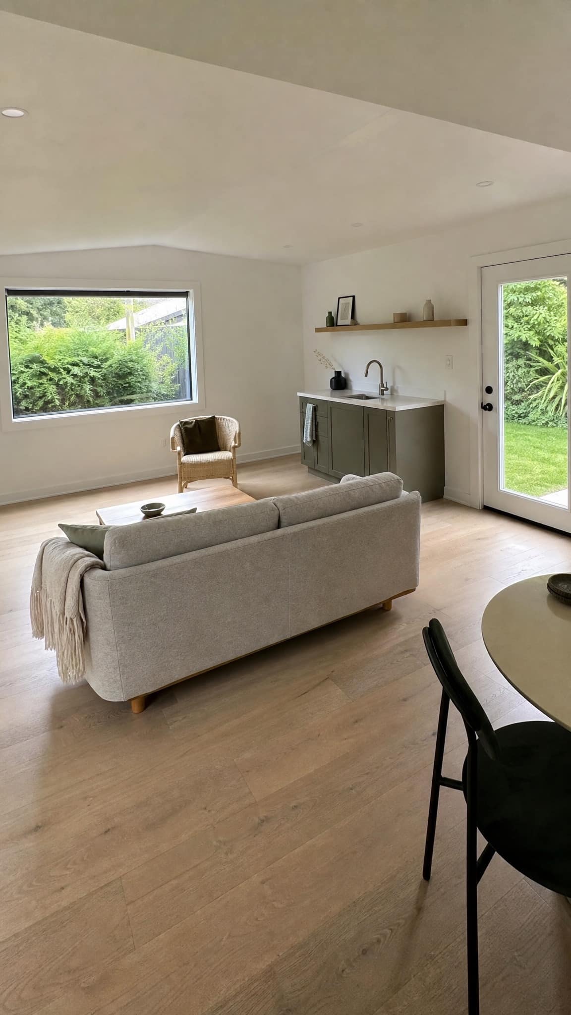 Inside a finished backyard studio, light oak floor and a big window onto the garden